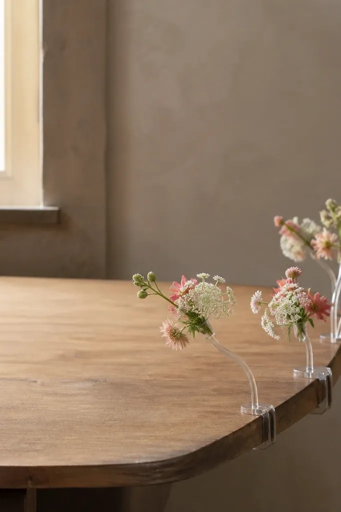 Small micro floral clusters attached to short clear stems, with the stems anchored at the table edge; clusters hover slightly above table height without spreading across the center.